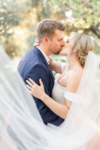 Bride kissing Groom with veil around them at El Chorro Scottsdale