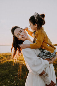 A mother holding her daughter in her arms while the girl puts a flower behind the mothers ear in Flower Mound, Texas