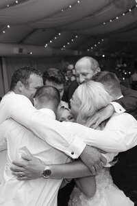Friends hugging on wedding dance floor