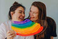 Two people smiling with a rainbow painted easel in front of them.