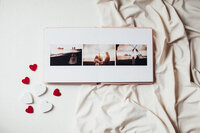 Photo album laid open on soft white sheets.