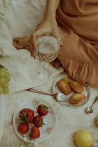 Detailed shot of a picnic setting on the grass with madeleines, strawberries, a fork and spoon