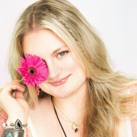 Beautiful young business owner poses with pink gerber daisy flower