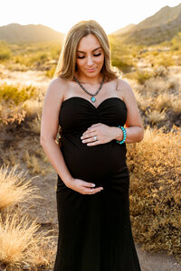 Stunning mom in fitted black gown, posing for maternity photograph