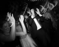 black and white photo with motion blur of wedding guests clapping or dancing taken by wedding photographer in minnesota tom thornton
