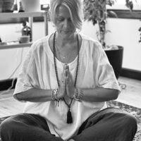 Connie Leimbach sitting crossed legged with hands at heart chakra black and white photo