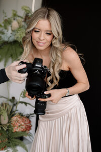 Leaning against a white wall, Emily stands with her hands on her hips. She's wearing all denim.