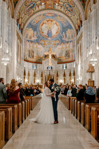 groom kissing bride as they walk down the aisle