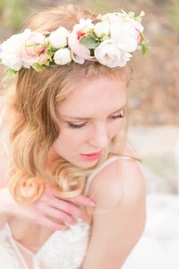 A bride has flowers in her hair and smiles off camera