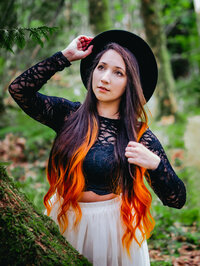 Colorful creative with orange hair posing among green forest foliage – vibrant and unique portrait by Mewphotovideo