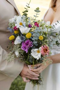 bride and groom both holding bridal bouquet together