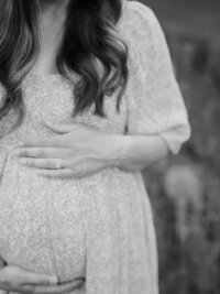 A close-up of a mother holding her pregnancy bump by Katie Stansfield Photography, a photographer who does Richmond newborn photography sessions.