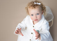 Toddler with blue eyes and blonde curls looking at the camera during a studio photoshoot in Hobart by Lauren Vanier Photography