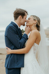 Bride and groom embrace as groom grabs brides chin to bring her into a romantic kiss