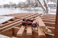 A Milwaukee drill on top of a partially completed deck frame on a snowy Minnesota winter day. 