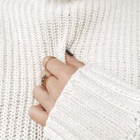 Brand photo of a hand clutching a white sweater