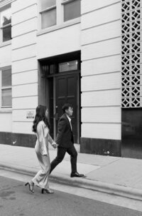 The couple walks hand in hand down the street during the engagement session