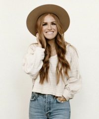 Smiling woman with long red hair wearing hat and white shirt with blue jeans- Romero Album Design