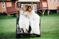 Two brides sitting on the backseat of a golfcart