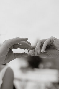 A couple holding their wedding bands up to the sky together on their wedding day.