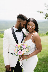 a bride and groom embrace on their wedding day in front of a mountain