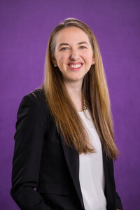 Headshot of a girl wearing a black sports coat on a blue background