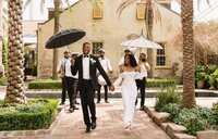bride and groom walking holding umbrellas