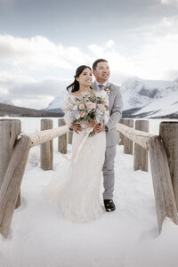 Couple shown on their wedding day embracing on a bridge at bow lake in banff, AB.
