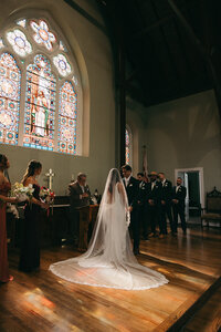 bride and groom at the alter with sunlight illuminating them through the stained glass window