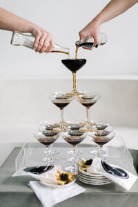 Cocktails being poured into pyramid of coupe glasses