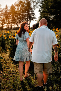 couple walks through a sunflower field in upstate ny