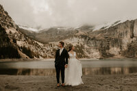 bride and groom holding hands looking at the surrounding mountains during elopement at Oeschinensee Lake in Switzerland