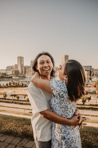 A couple hugging on a rooftop as they smile 