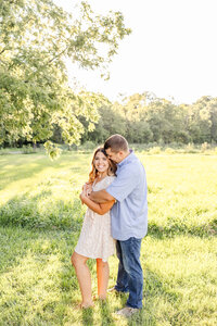 Couple stand snuggling wrapped in each other in a grassy field in Russellville, Ohio.