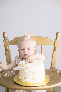 one year old in gold highchair reaches for her cake, Central Indiana Family photographer