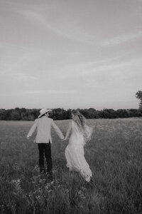 couple running through field at their ranch wedding