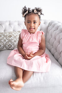 A little girl sitting on a sofa during a family photoshoot  in a studio in Alabama