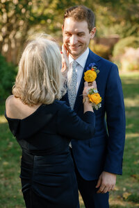 A person fixing a groom's boutonniere