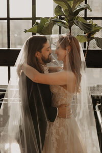 bride and groom share a kiss under veil