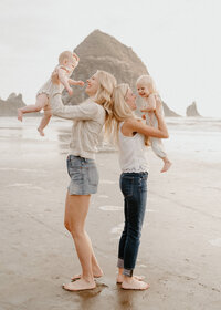 friends holding babies at coast