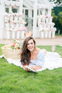 Abby Manawes in a black top sitting in a white chair with a book