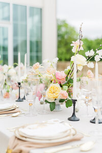 Wedding table setting with neutral linens and yellow and pink floral arrangements
