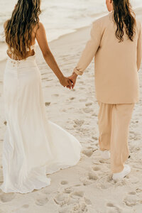 couple holds hands on beach