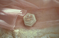 wedding ring box detail photo sitting on pink ribbon and white wedding dress