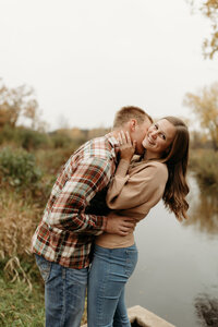 man and woman kissing by lake