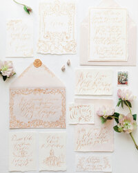 Flat lay of elegant blush and gold wedding invitations with flowers