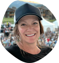 Mandi Gum, art director, designer and owner of Mandi Gum Design. She has brown hair and green eyes and is wearing a dark blue trucker hat.