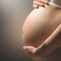 A massage therapist gently massages a pregnant person's back, providing relief and relaxation. This prenatal massage service is available at Bodyology Therapeutic Massage in Boise and Eagle.