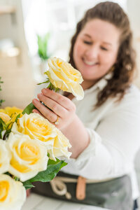 Brand photo of a florist pulling a yellow rose from a bucket of fresh, uncut flowers