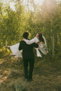 groom carrying bridge down nature path